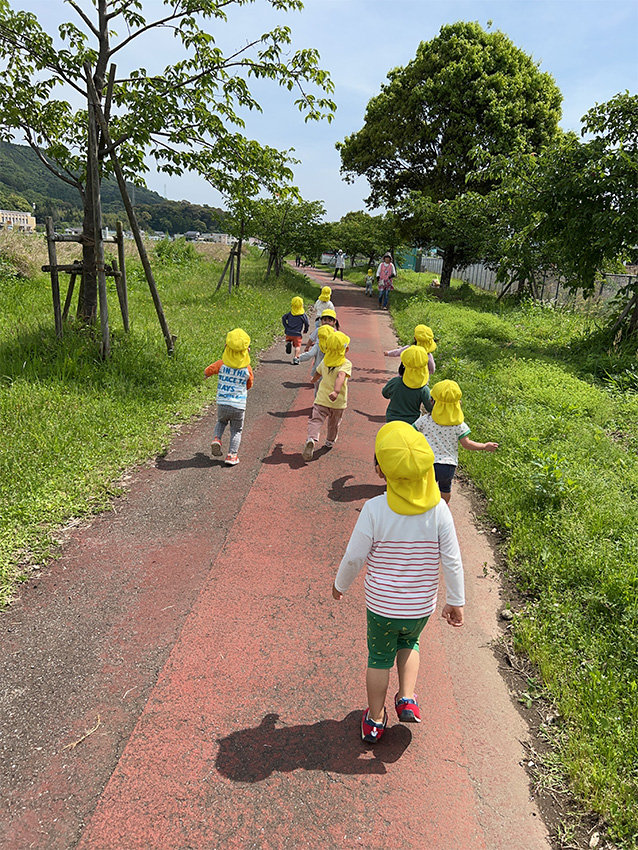 植物に囲まれた歩道をかける子どもたち